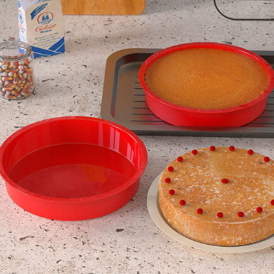 Ensemble de moules en silicone ronds rouges avec pate versee et gateau cuit.