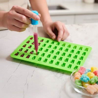 Femme préparant des bonbons en forme ourses dans moules en silicone vert