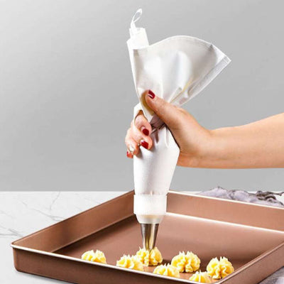 Main utilisant une poche à douille en coton lavable avec embout en acier inoxydable pour décorer des biscuits avec de la crème