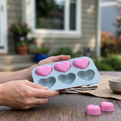 Moules en silicone en forme de cœur avec chocolats roses démoulés sur une table