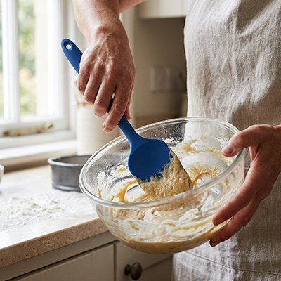 Spatule Cuisine en silicone bleue utilisée pour mélanger une pâte dans un bol
