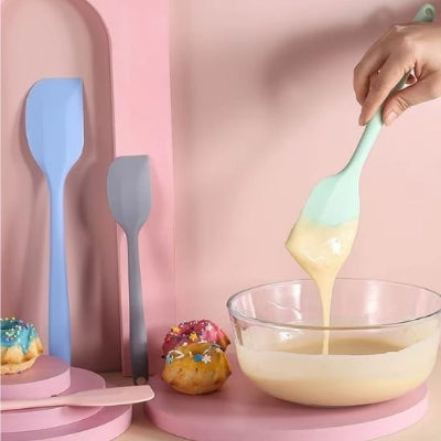 Spatule de cuisine en silicone utilisée pour mélanger une pâte à gâteau dans un bol en verre