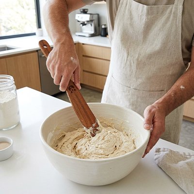 Spatule en bois utilisée pour mélanger une pâte dans grand bol blanc