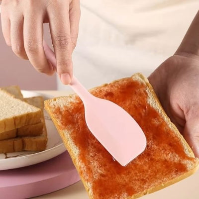 Spatule en silicone rose utilisée pour étaler de la confiture sur une tranche de pain grillé