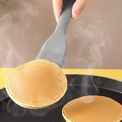 Spatule en silicone utilisée pour retourner des pancakes dans une poêle chaude pendant la cuisson