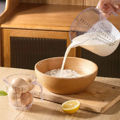 Verre doseur gradué transparent utilisé pour verser lait dans bol de préparation