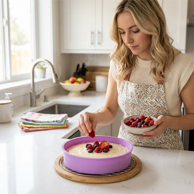 femme mettant un morceau de fruit sur une preparation dans un moule à gateau rond en silicone