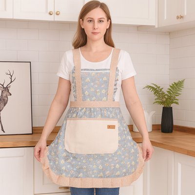 Femme portant tablier de cuisine bleu motif floral avec grande poche avant debout dans cuisine