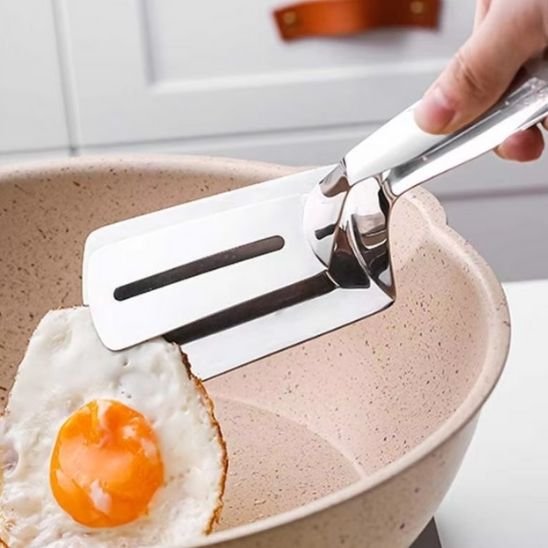 Spatule en acier inoxydable soulevant œuf plat dans poêle