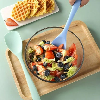 Spatule en silicone​ mélangeant de la salade dans un saladier en verre 