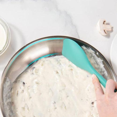 Spatule en silicone​ mélangeant farine dans un plat en aluminium