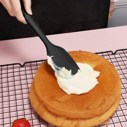 Spatule noire utilisée pour étaler la crème sur un gâteau