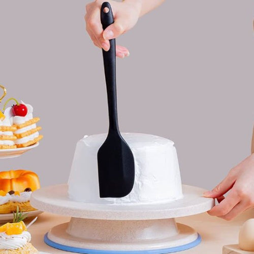 Spatule noire utilisée pour lisser le glaçage d’un gâteau